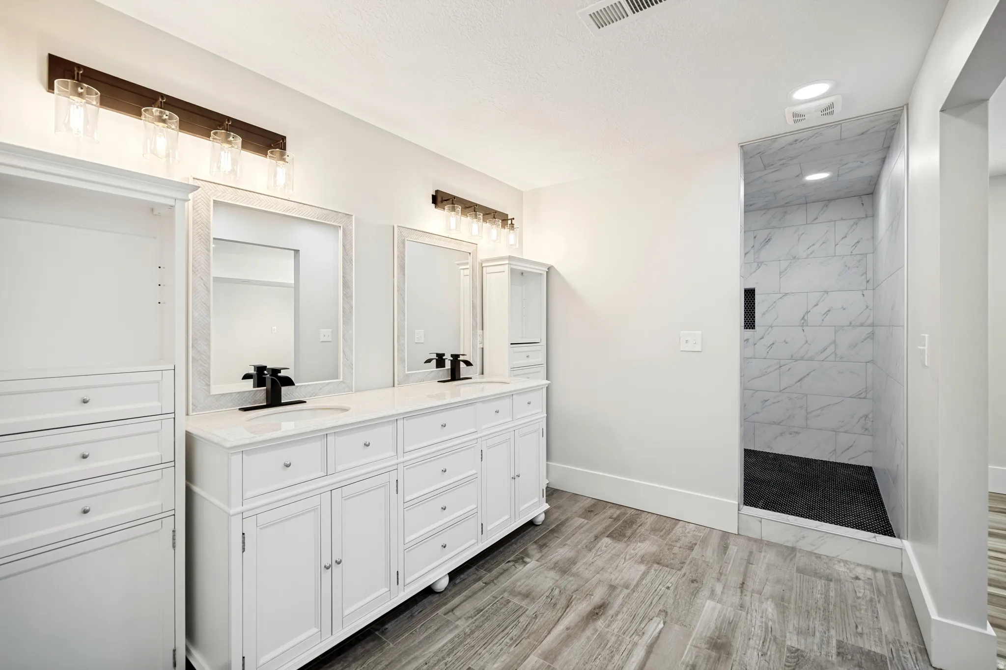 Dual vanity with white cabinetry and integrated sinks, quartz countertops, and matte black fixtures