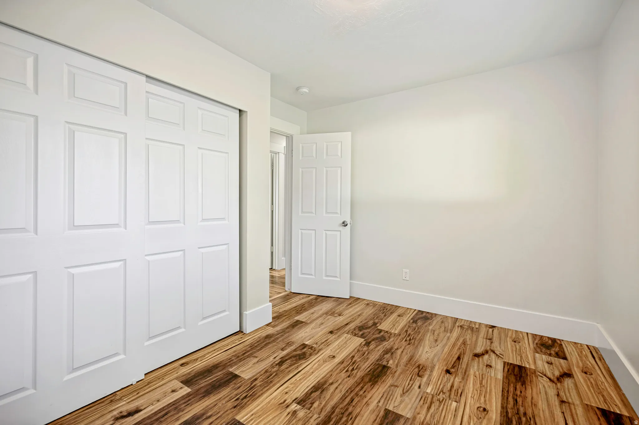 Room featuring wood-finish flooring, crisp white walls, and a recessed ceiling light