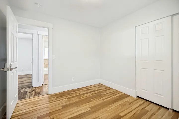 Room featuring wood-finish flooring, white walls, and white baseboards