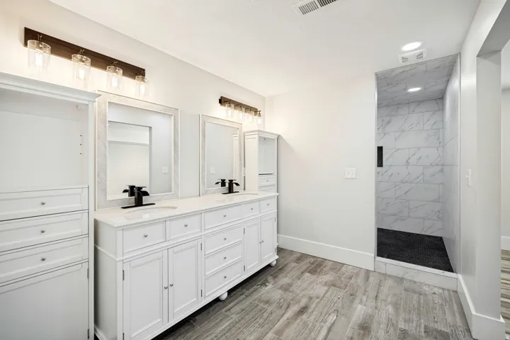 Dual vanity with white cabinetry and integrated sinks, quartz countertops, and matte black fixtures