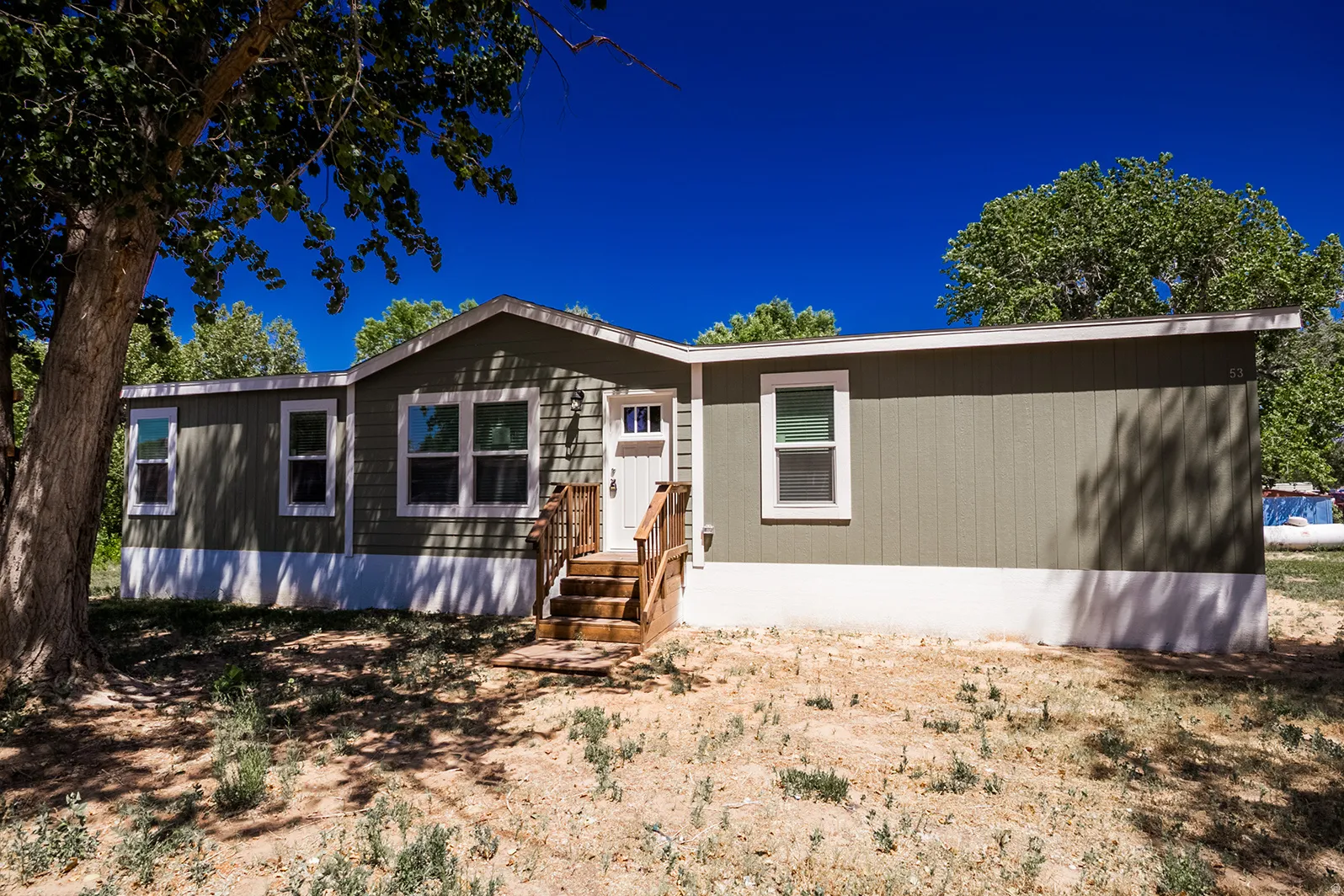Single-story residence featuring green siding with white trim, a white entry door, and a multi-pane window