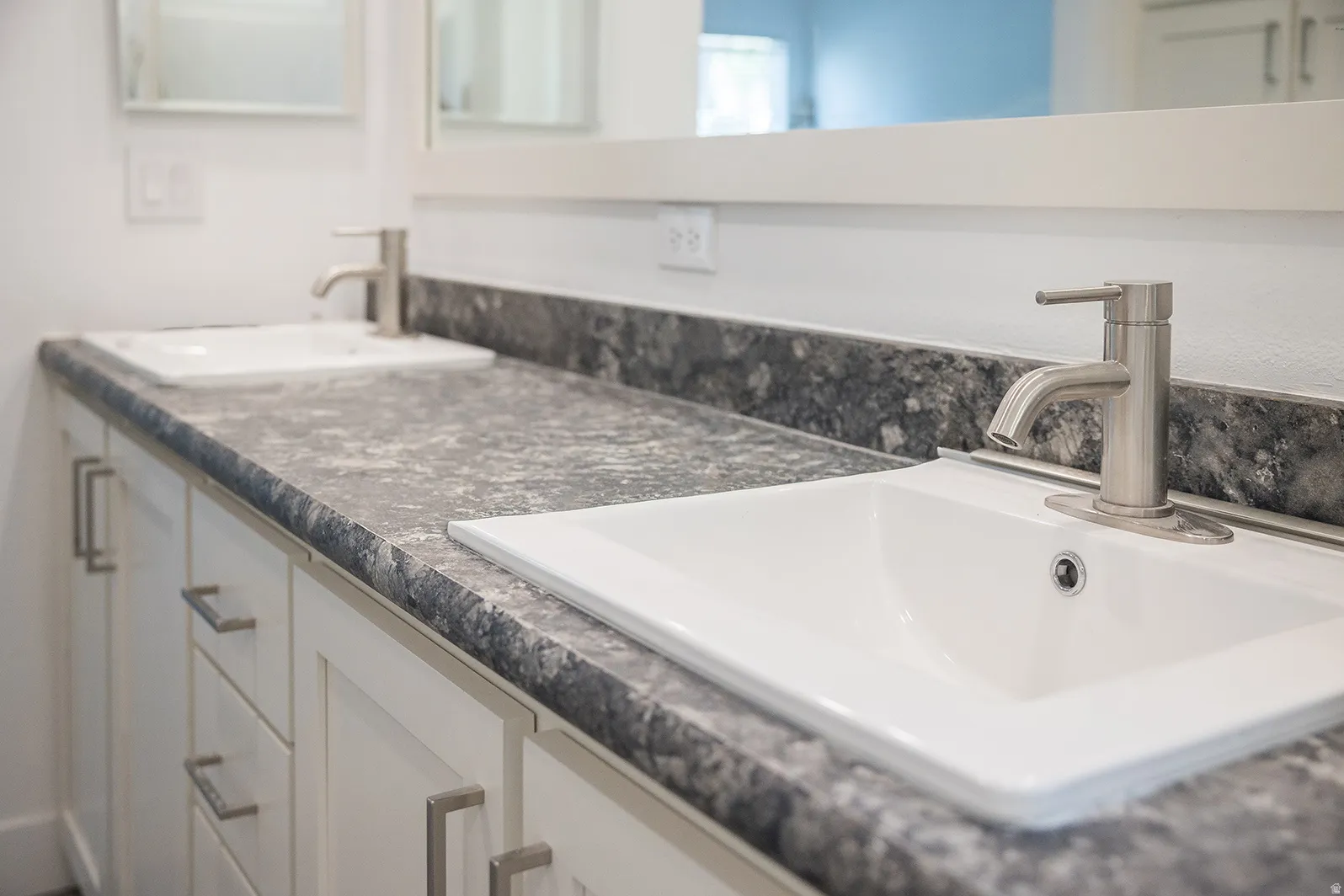 Dual vanity with white cabinetry, brushed nickel hardware, and dark patterned countertops
