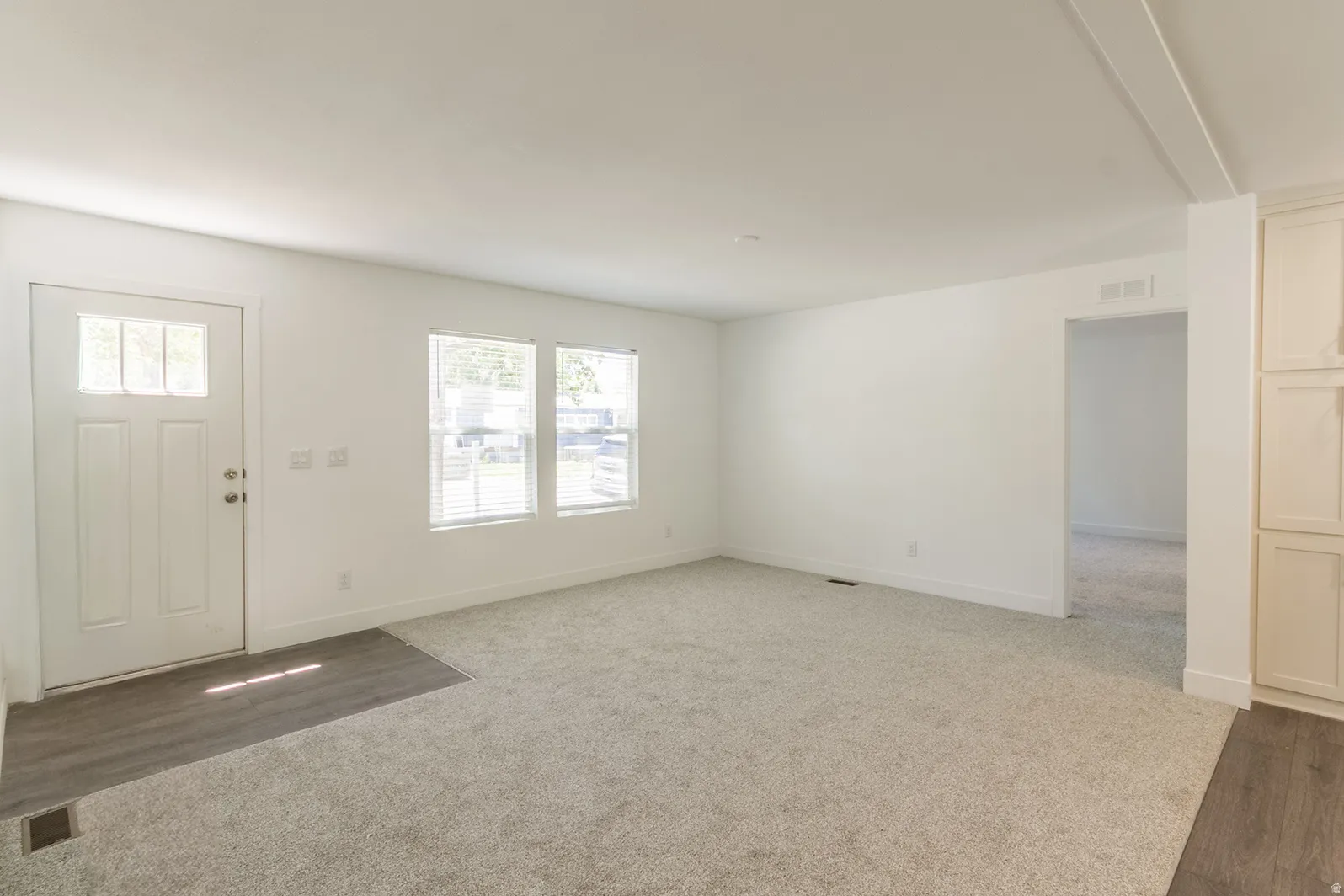 Bright interior space featuring white walls and a light-colored carpet