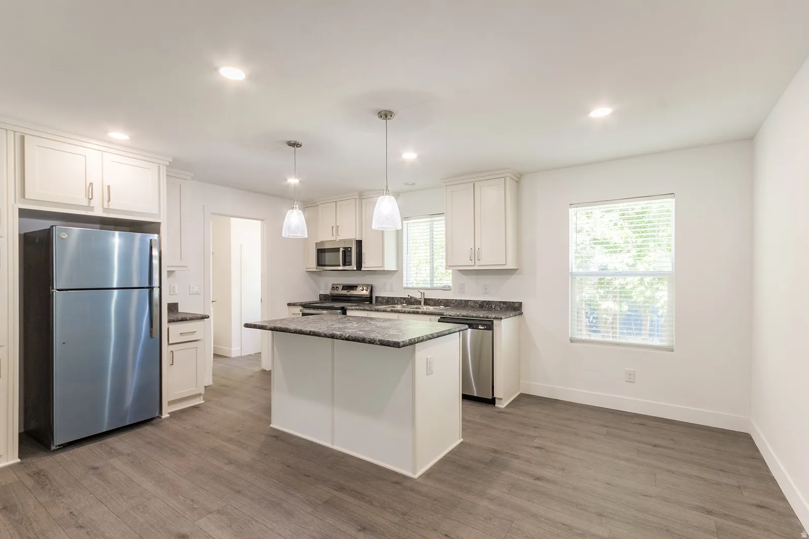 Kitchen featuring a central island, white cabinetry, dark stone countertops, and stainless steel appliances
