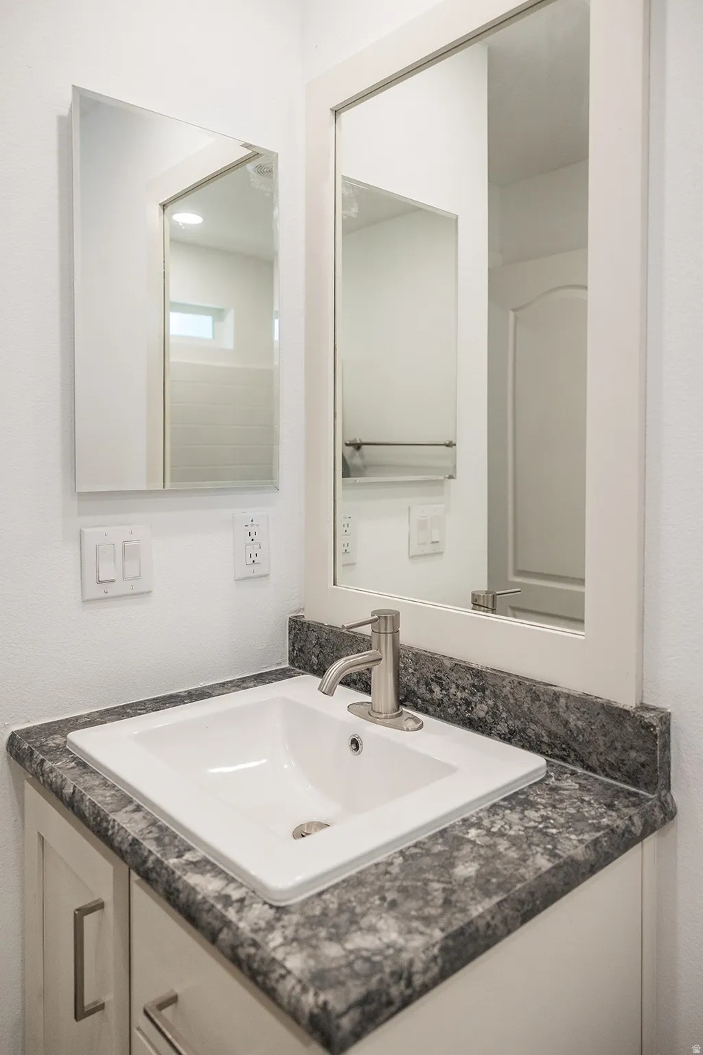 Vanity with integrated sink, speckled countertop, and brushed nickel faucet