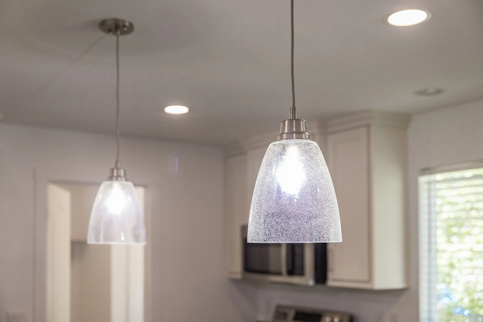 Contemporary pendant lighting featuring clear textured glass shades and brushed nickel hardware