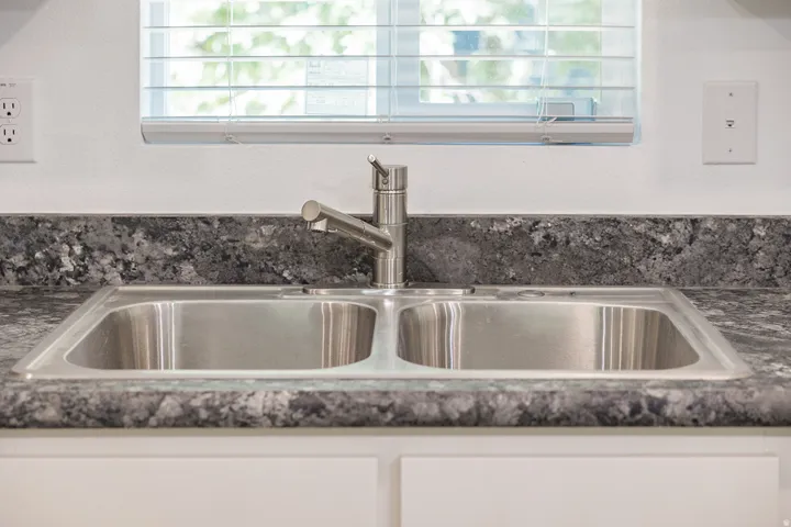 Dual-basin stainless steel sink with a single-handle faucet, set into a dark speckled countertop