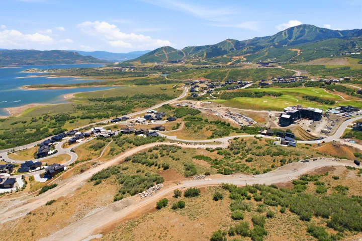 Expansive aerial landscape featuring a large body of water, rolling hills, and a mountainous backdrop