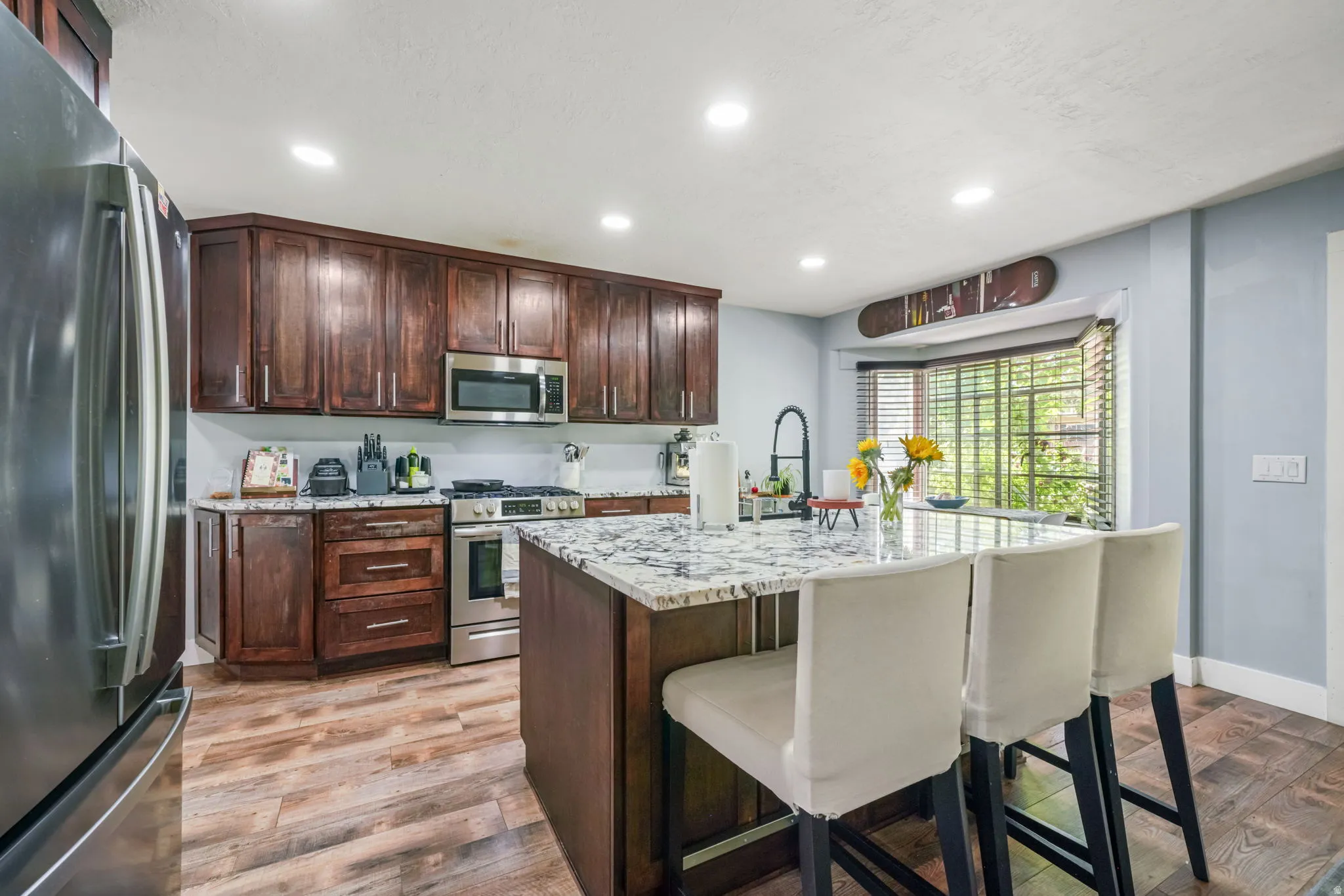 Kitchen featuring dark wood cabinetry, stainless steel appliances, and a central island with a granite-style countertop