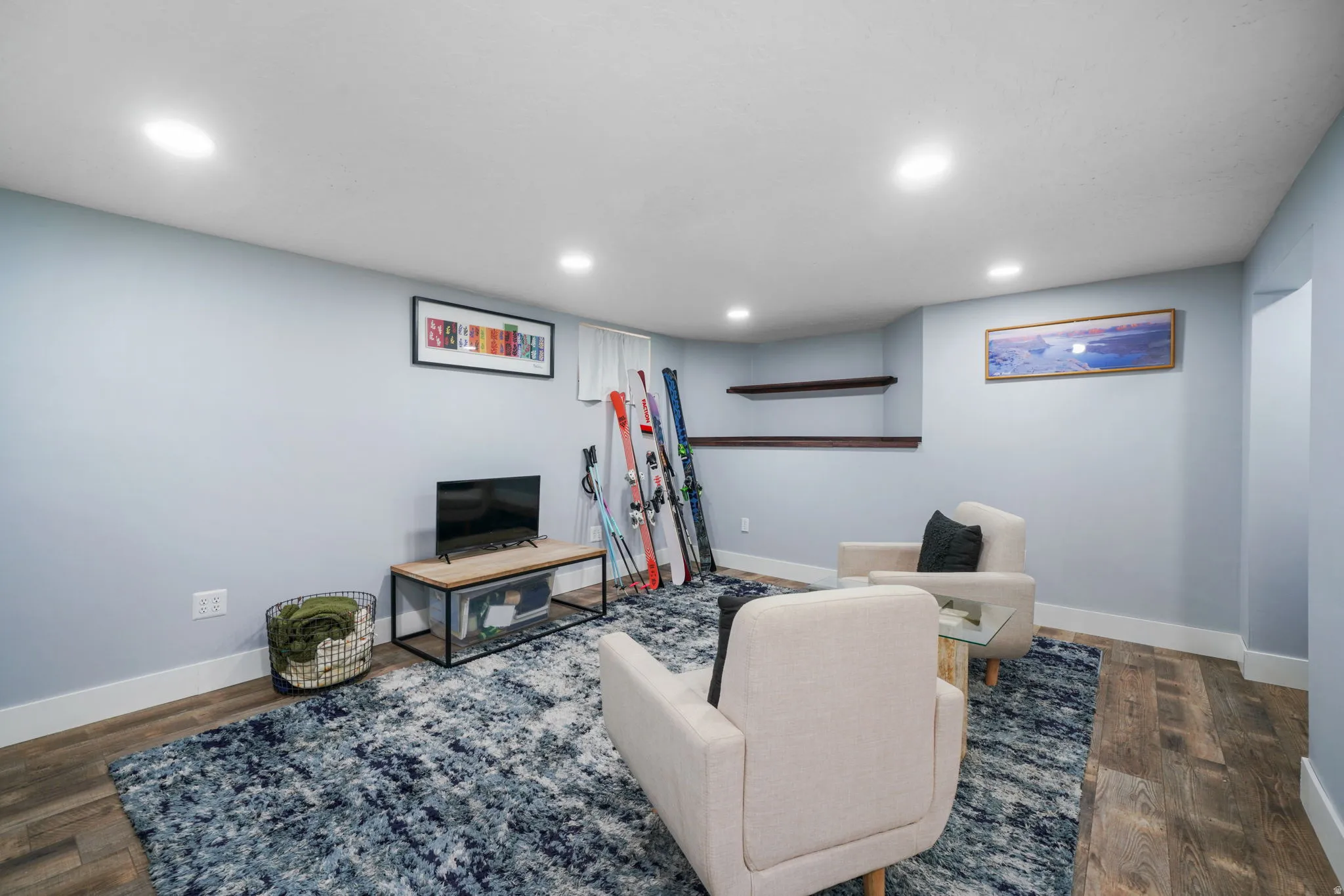 Brightly lit room featuring recessed ceiling lights, light blue painted walls, wood-finish flooring, and white baseboards