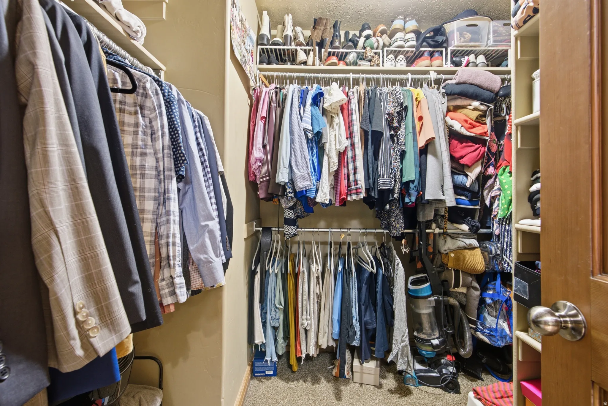 Walk-in closet featuring multiple hanging rods, overhead shelving, and built-in vertical storage compartments