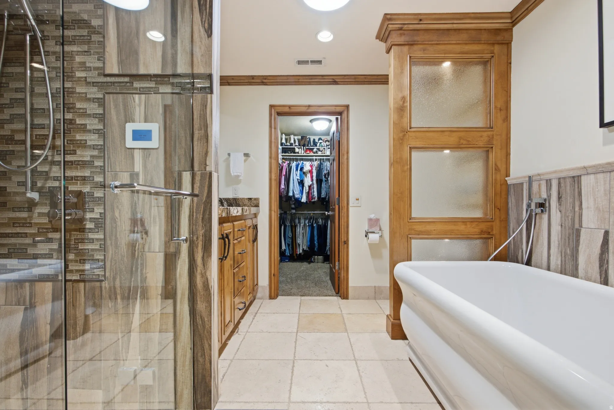 Shower enclosure with glass panel, integrated digital shower control, and mosaic tile accents