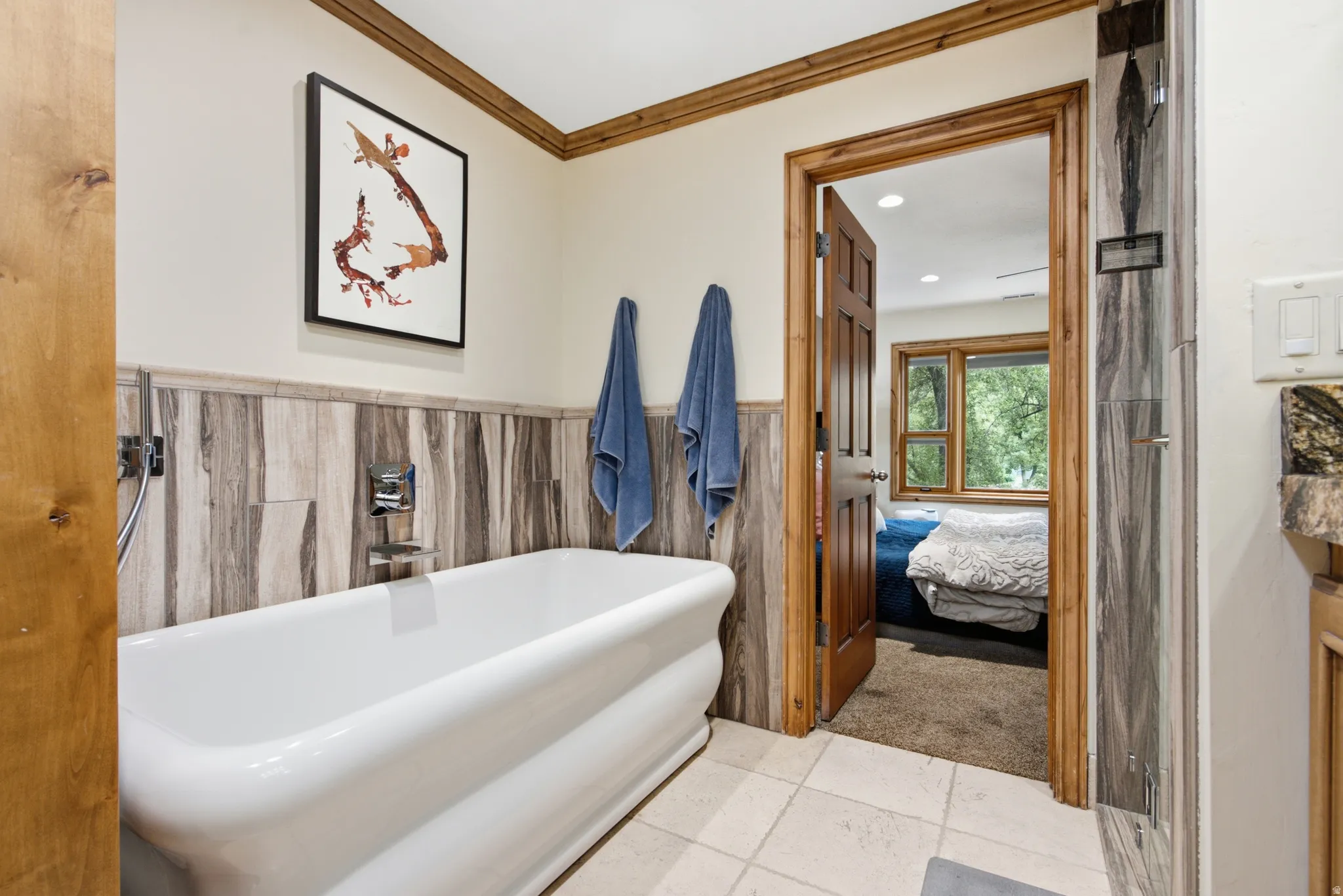 Freestanding soaking tub featuring chrome fixtures, wood-finish wainscoting, and tile flooring