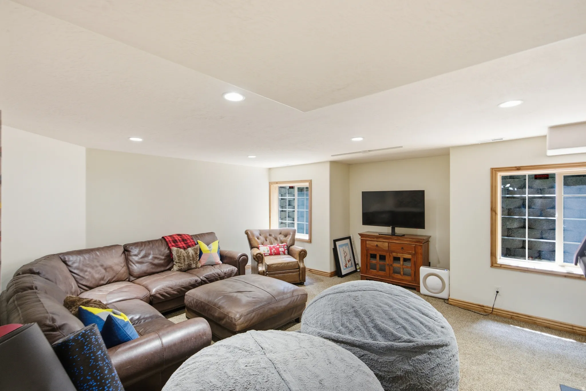 Recessed lighting illuminates this space featuring two framed windows with wood trim and light-colored walls