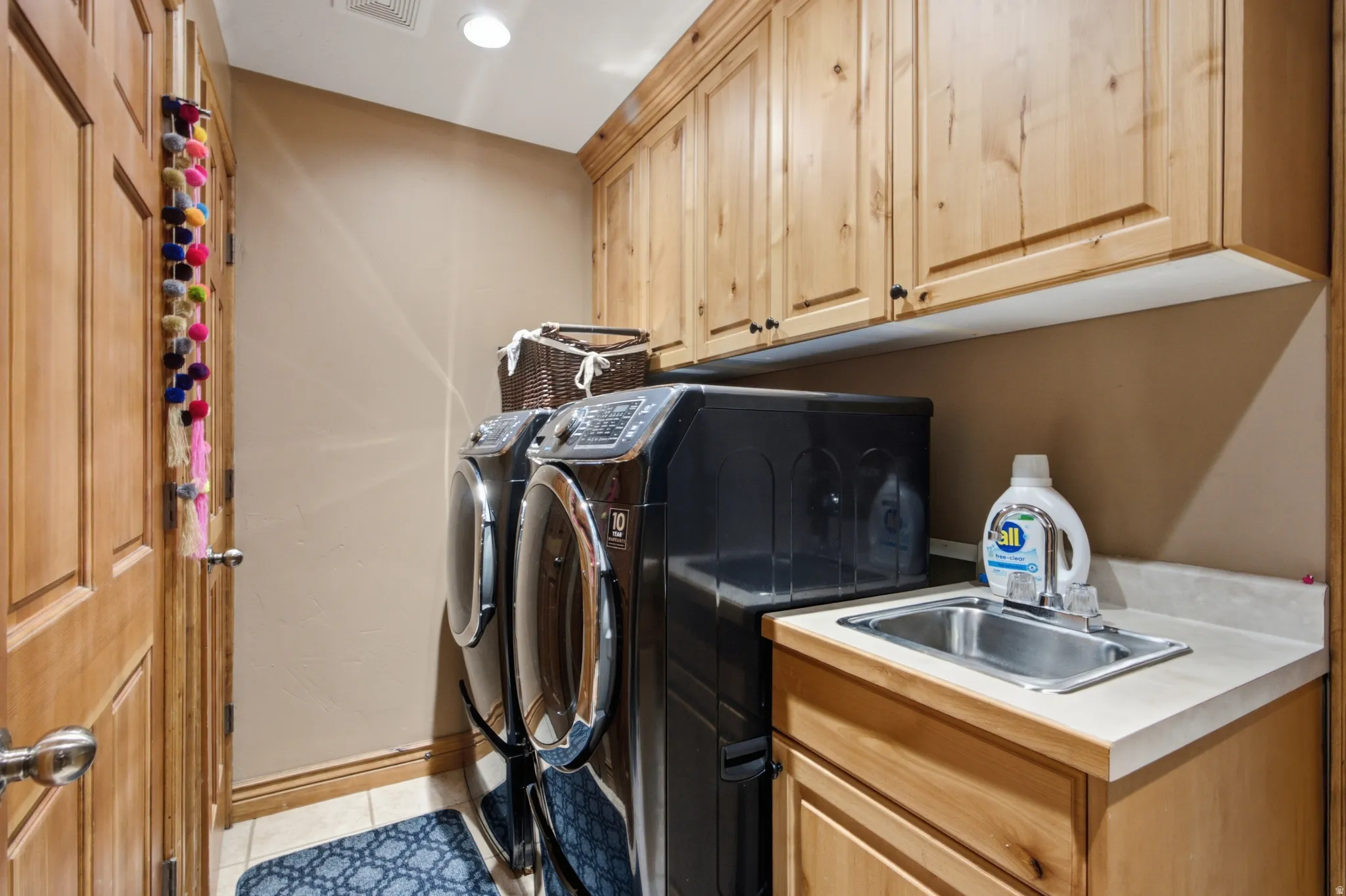 Laundry area featuring wood cabinetry, a utility sink with a light-toned countertop, and recessed lighting