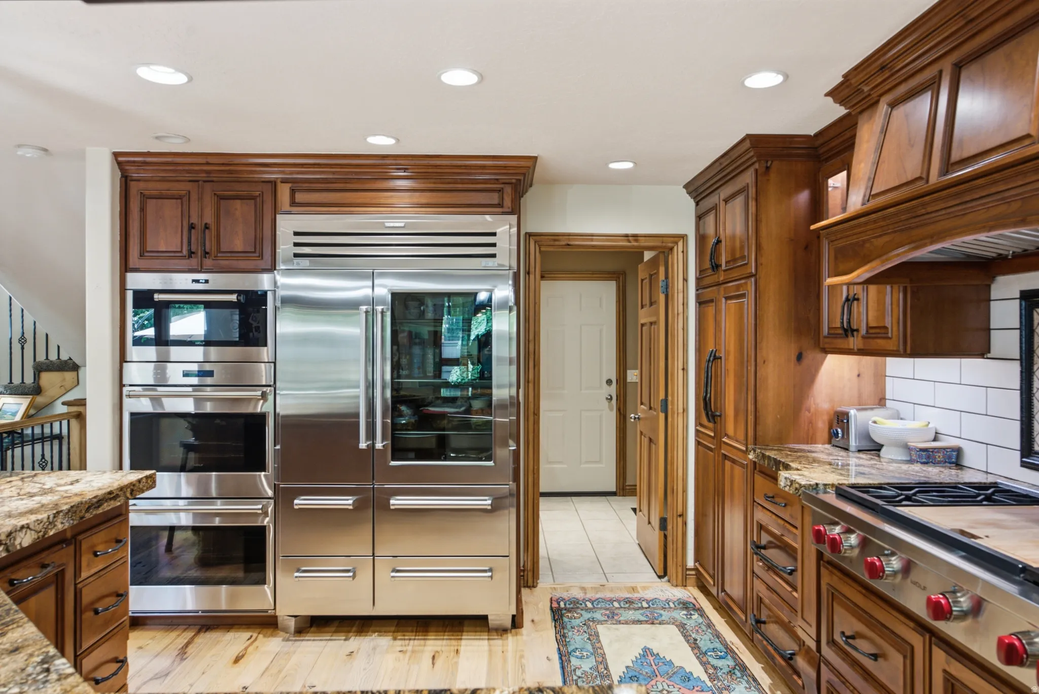 Gourmet kitchen featuring custom wood cabinetry, stainless steel appliances, a built-in double oven, paneled refrigerator, and stone countertops