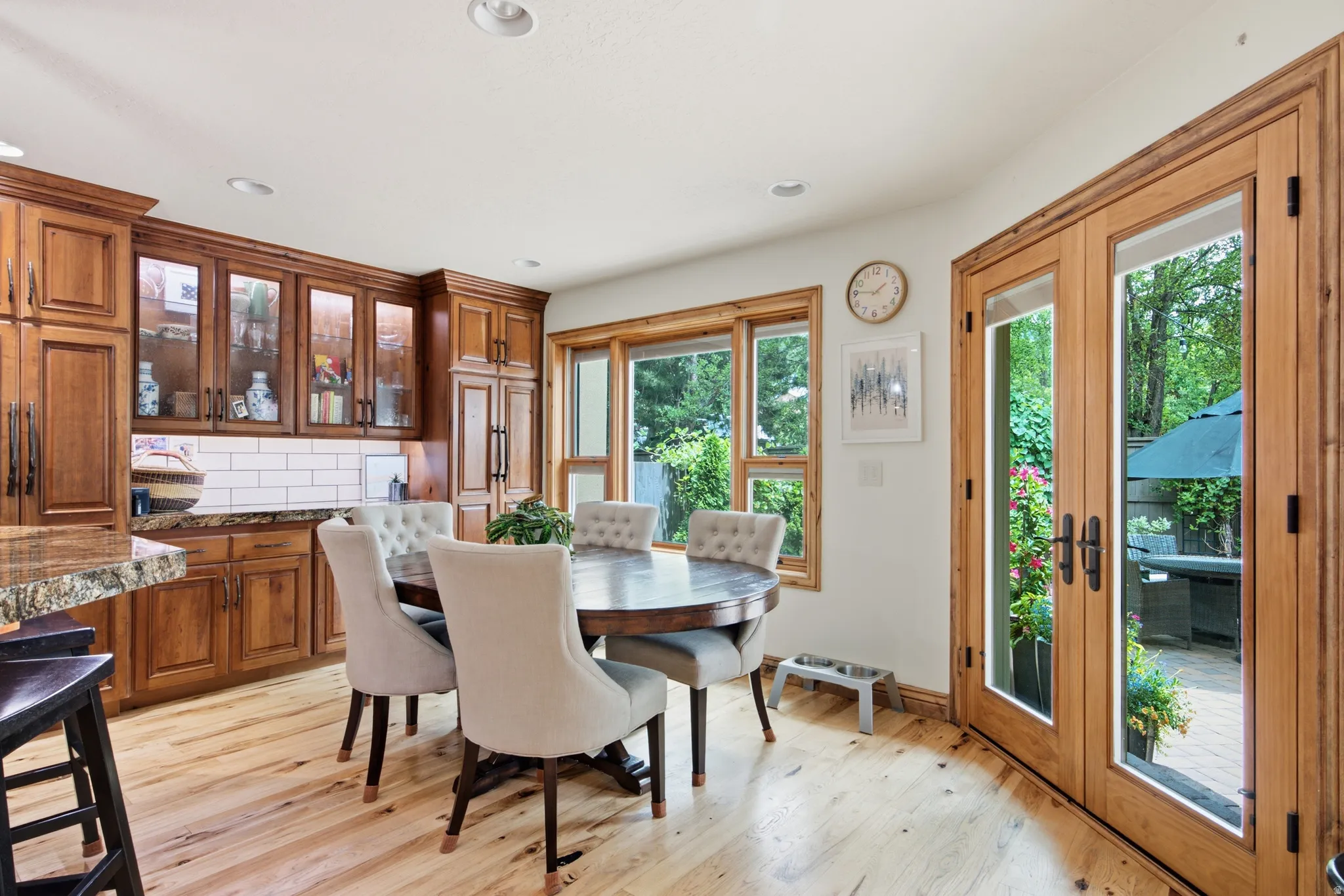 Hardwood flooring throughout, featuring a kitchen with wood cabinetry, glass-front upper cabinets, and a subway tile backsplash