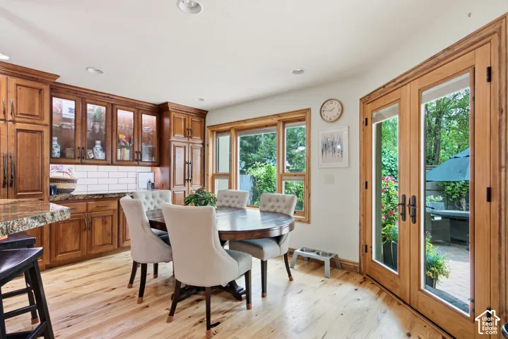 Hardwood flooring throughout, featuring a kitchen with wood cabinetry, glass-front upper cabinets, and a subway tile backsplash