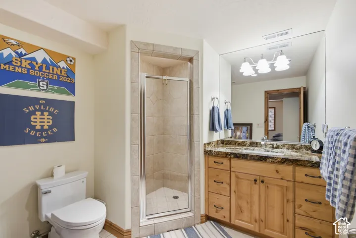 Full bathroom featuring a walk-in shower with glass enclosure, a wood-finish vanity with an integrated sink and stone-look countertop, a large wall-mounted mirror, and a white toilet