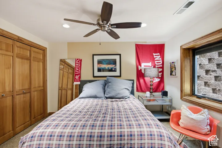Recessed lighting illuminates this room featuring wood-finish bi-fold closet doors, a wood-trimmed window, and a ceiling fan with integrated lighting