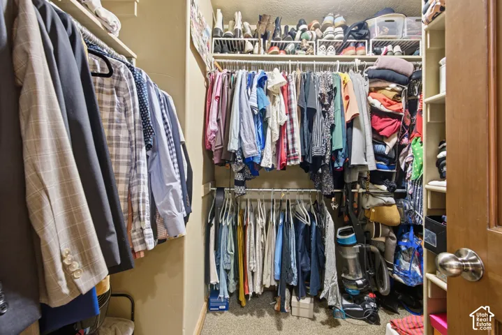 Walk-in closet featuring multiple hanging rods, overhead shelving, and built-in vertical storage compartments