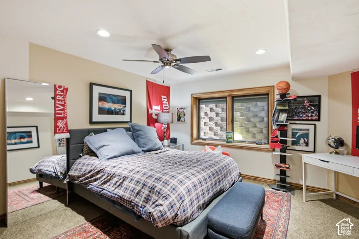 Recessed lighting and a ceiling fan illuminate this carpeted room