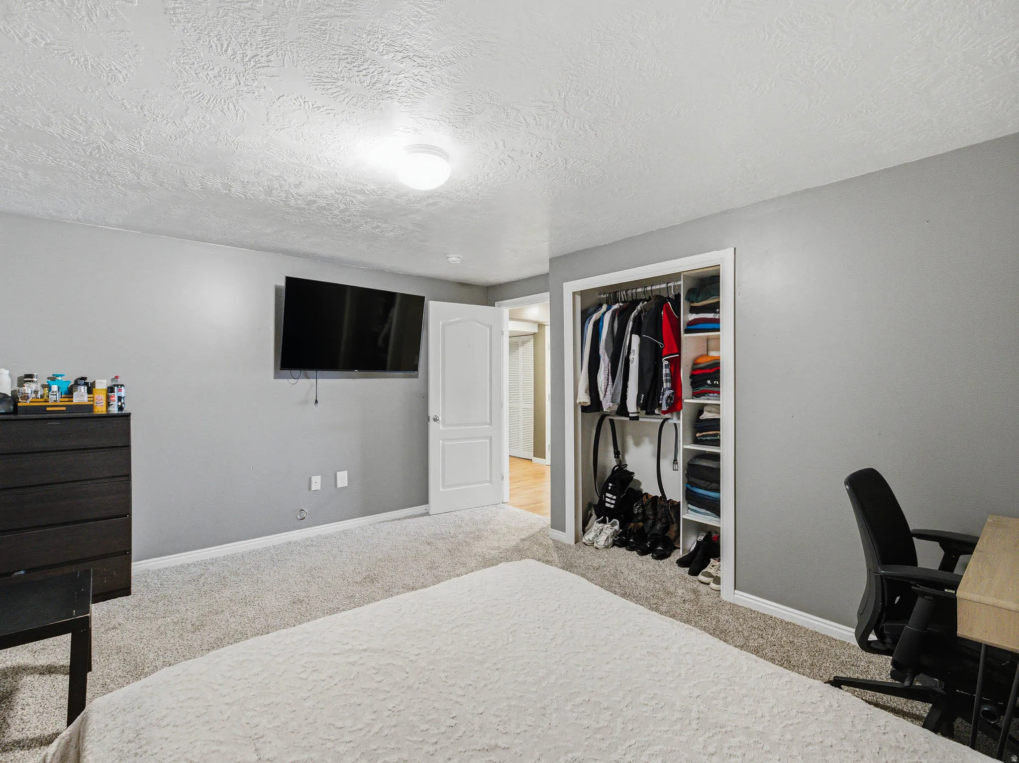 Carpeted bedroom with neutral gray walls and a textured white ceiling
