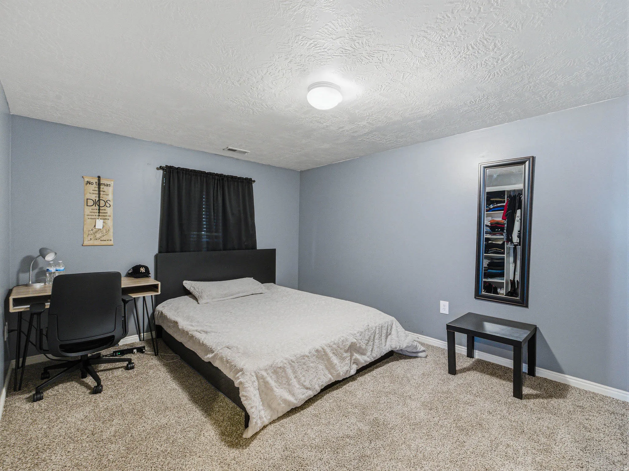 Carpeted room with light blue walls and a textured white ceiling