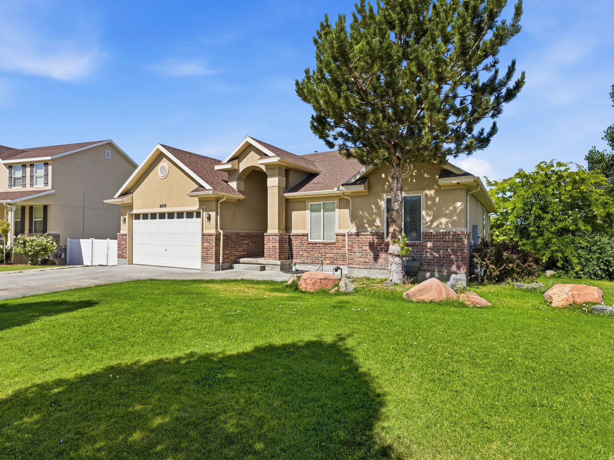 Single-story residence featuring a two-car garage, brick and stucco exterior, and a prominent front entrance with an arched portico