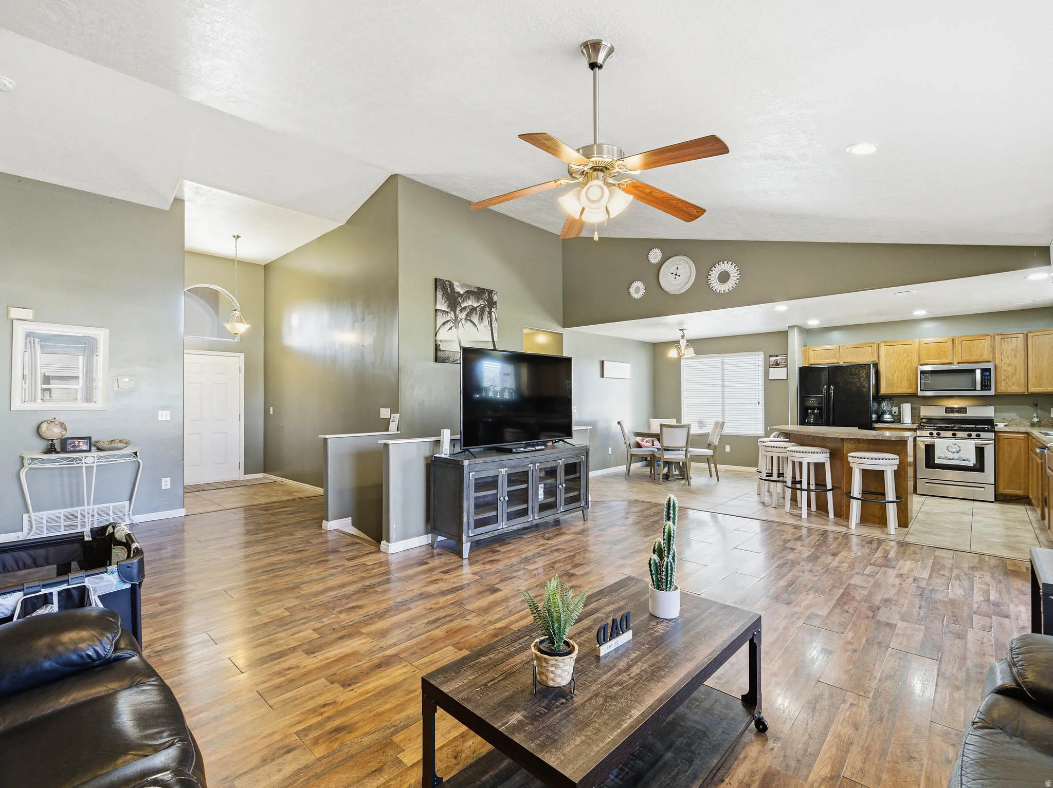 Open-concept living space featuring wood-finish flooring, vaulted ceilings, and a ceiling fan