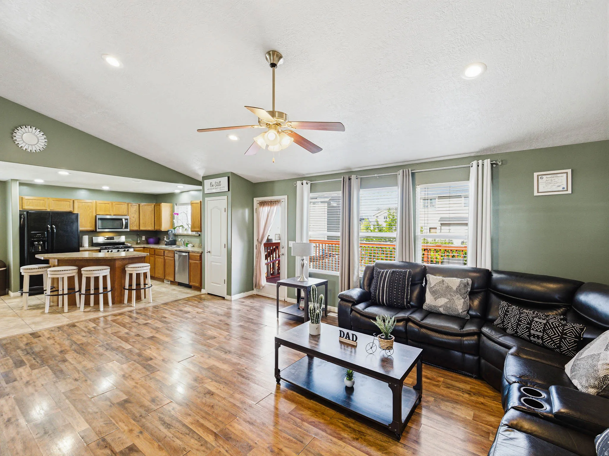 Open-concept living area featuring wood-finish flooring, vaulted ceilings, and recessed lighting