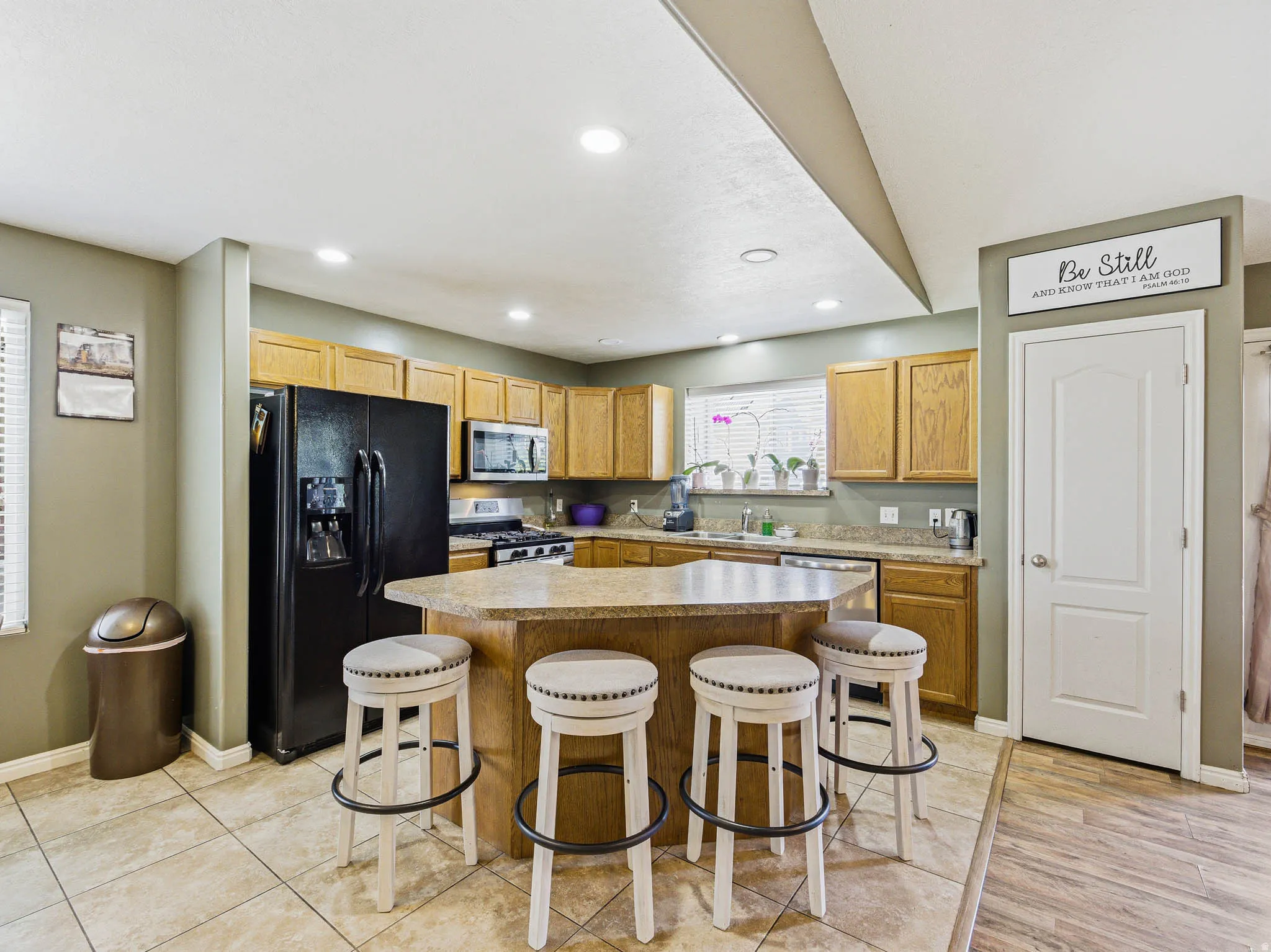 Kitchen featuring a central island with countertop seating, recessed lighting, tile flooring, and natural wood cabinetry