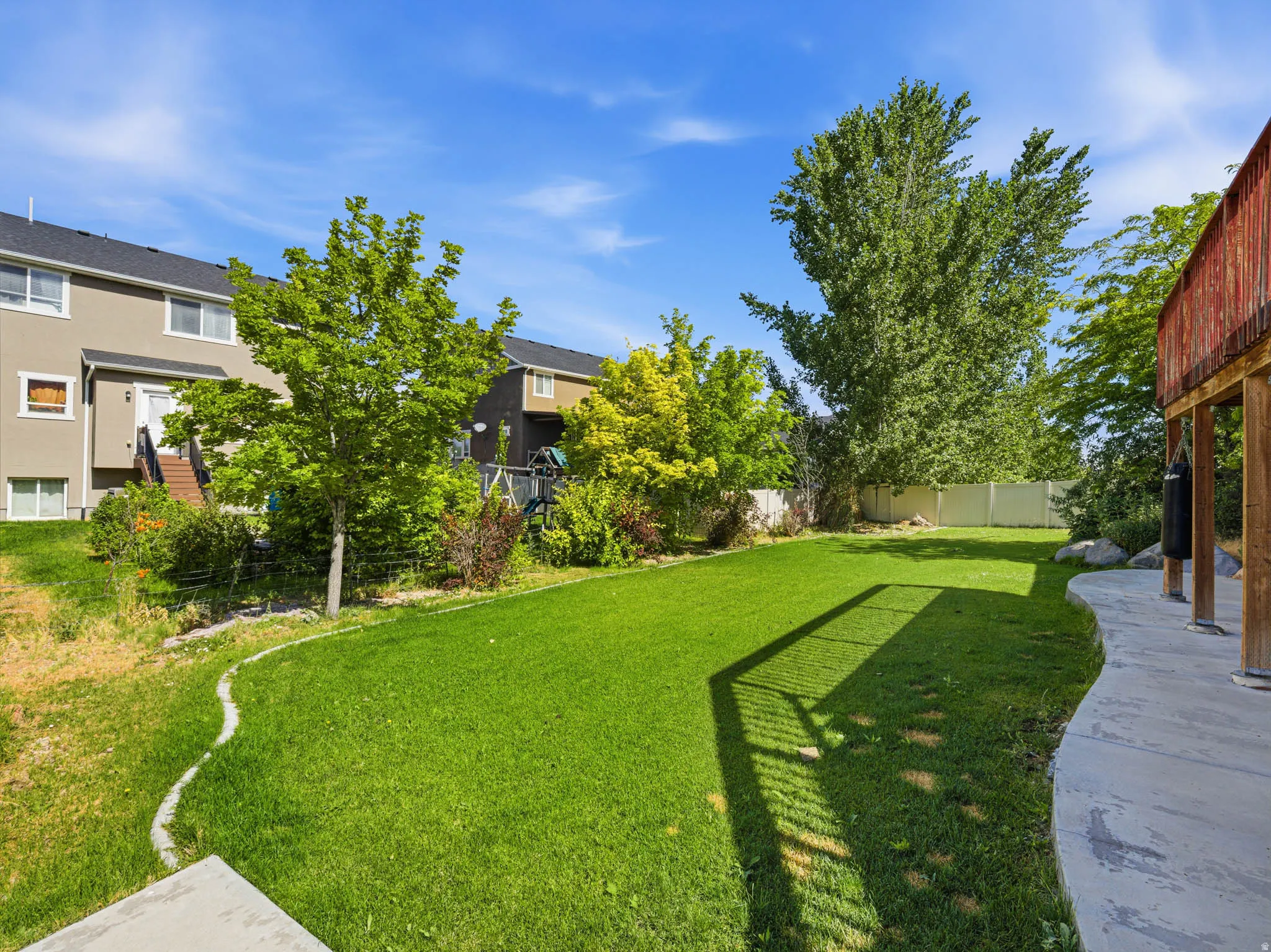 Expansive green lawn with mature trees and a privacy fence