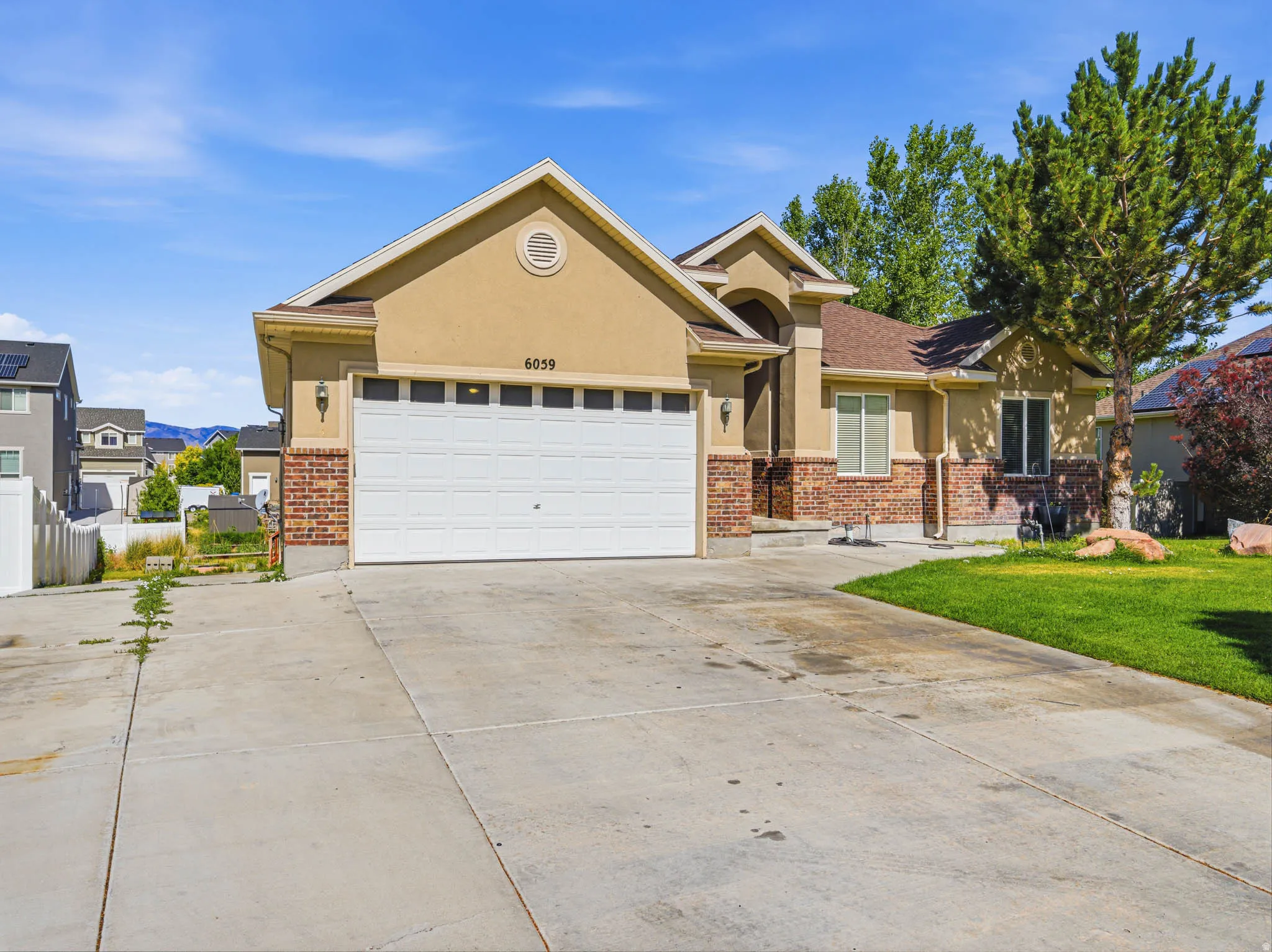 Two-story residence featuring a stucco and brick facade, an attached two-car garage, and a concrete driveway