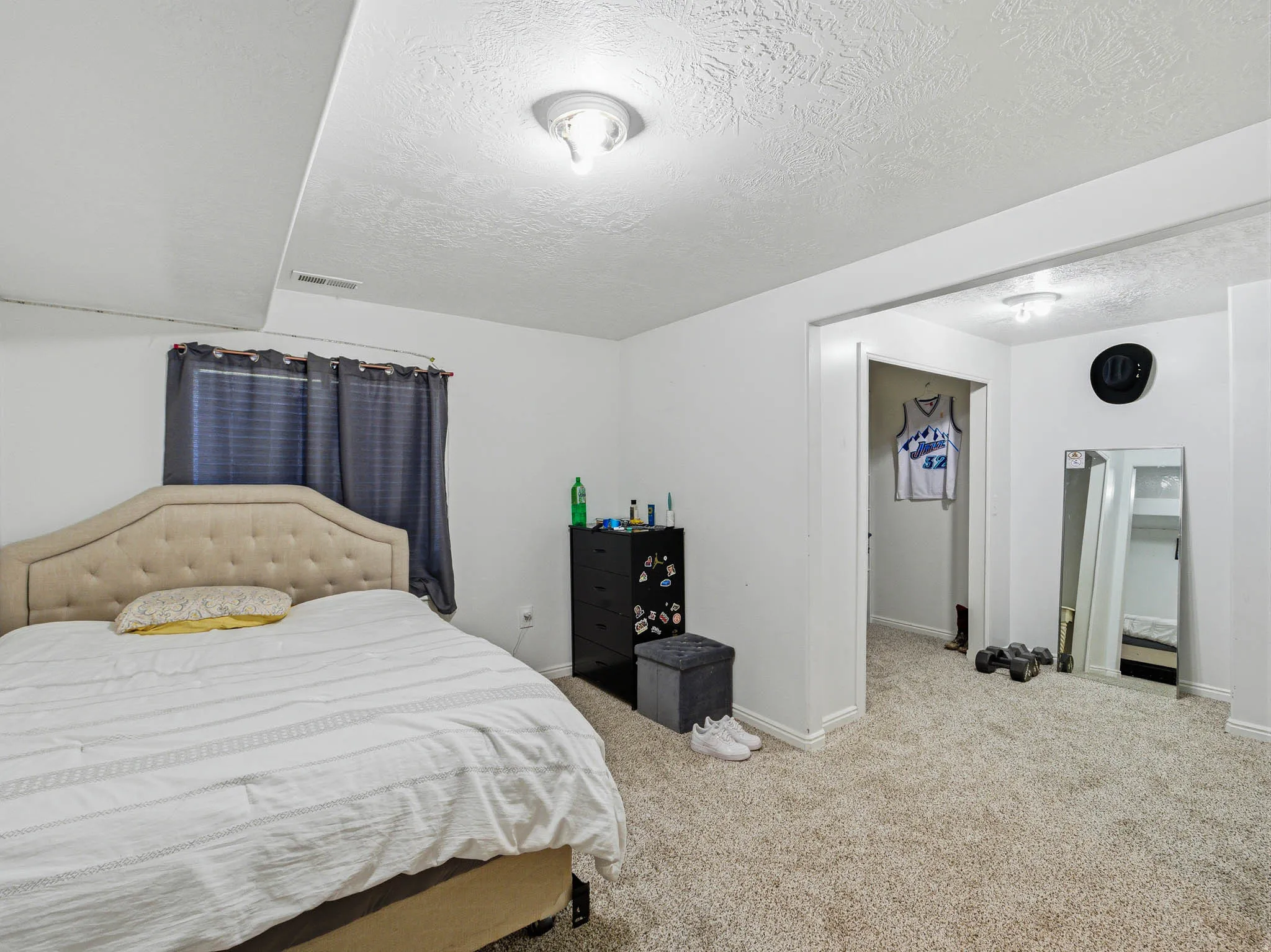 Carpeted room with a window featuring dark curtains, an upholstered headboard, and recessed lighting