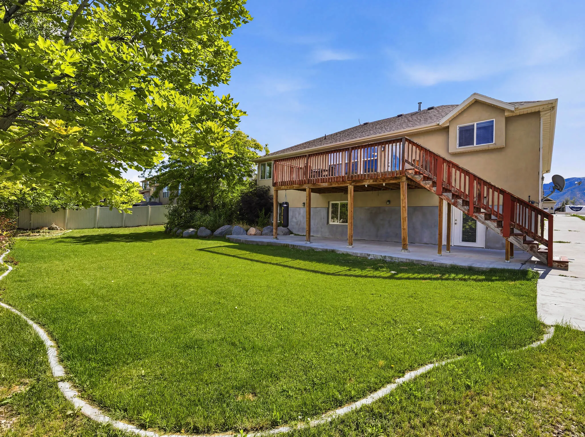 Expansive backyard featuring a manicured lawn and mature trees
