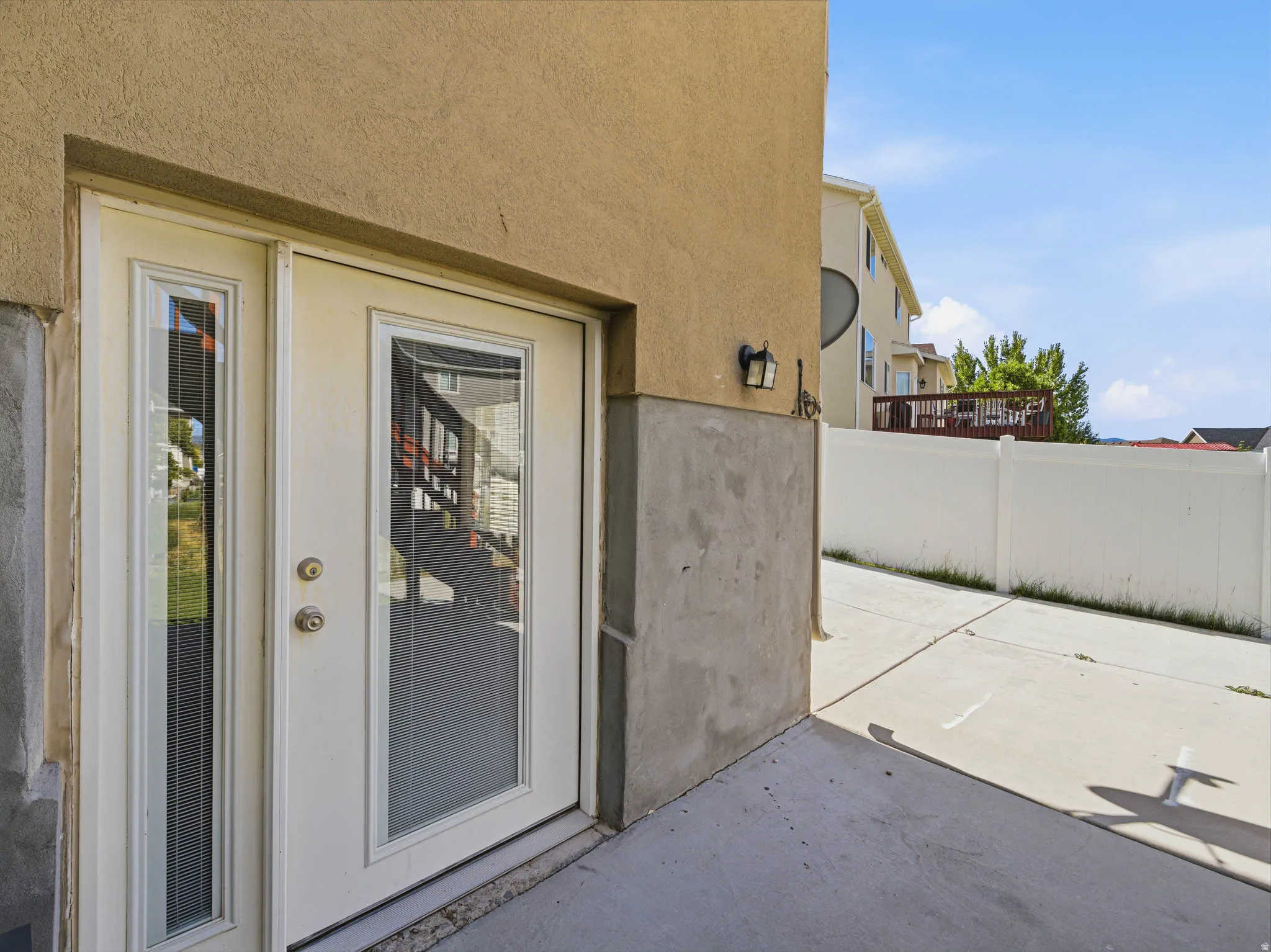Exterior access point featuring a dual-pane glass door and a coordinating sidelight, set into a stucco-finish wall