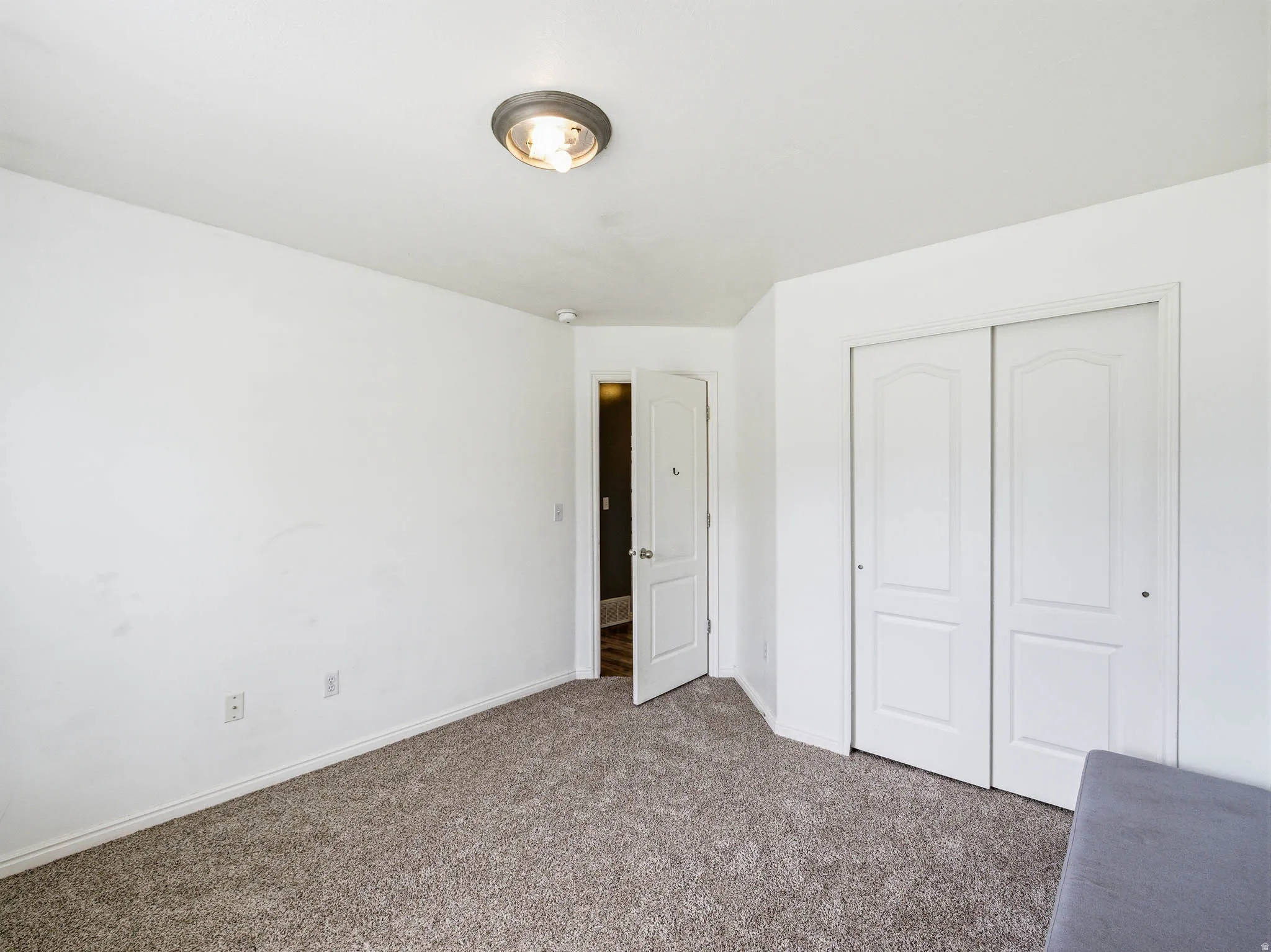 Carpeted interior room featuring white painted walls and a flush-mount ceiling light