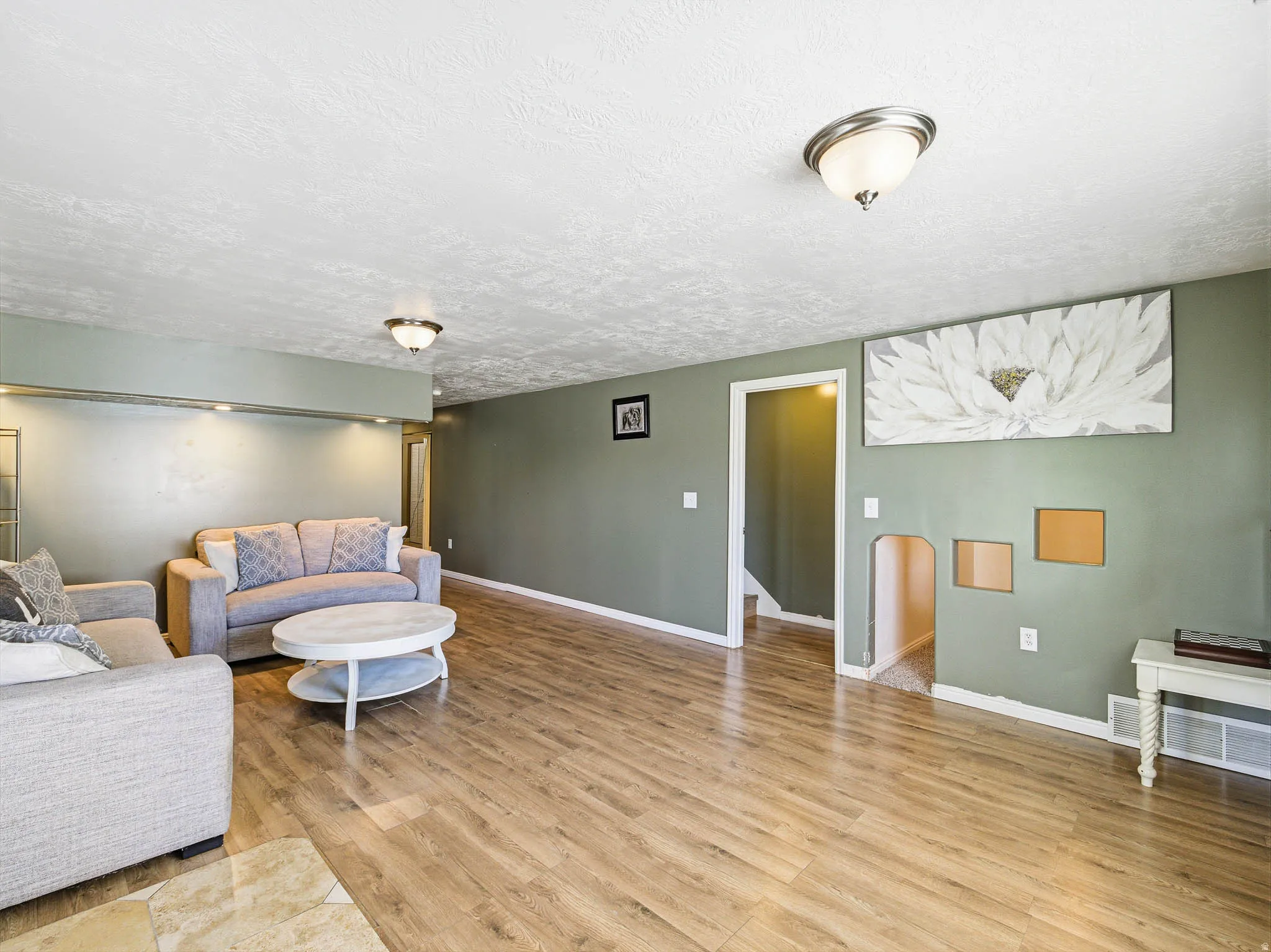 Spacious interior with wood-finish flooring, two ceiling-mounted dome lights, and recessed lighting accents