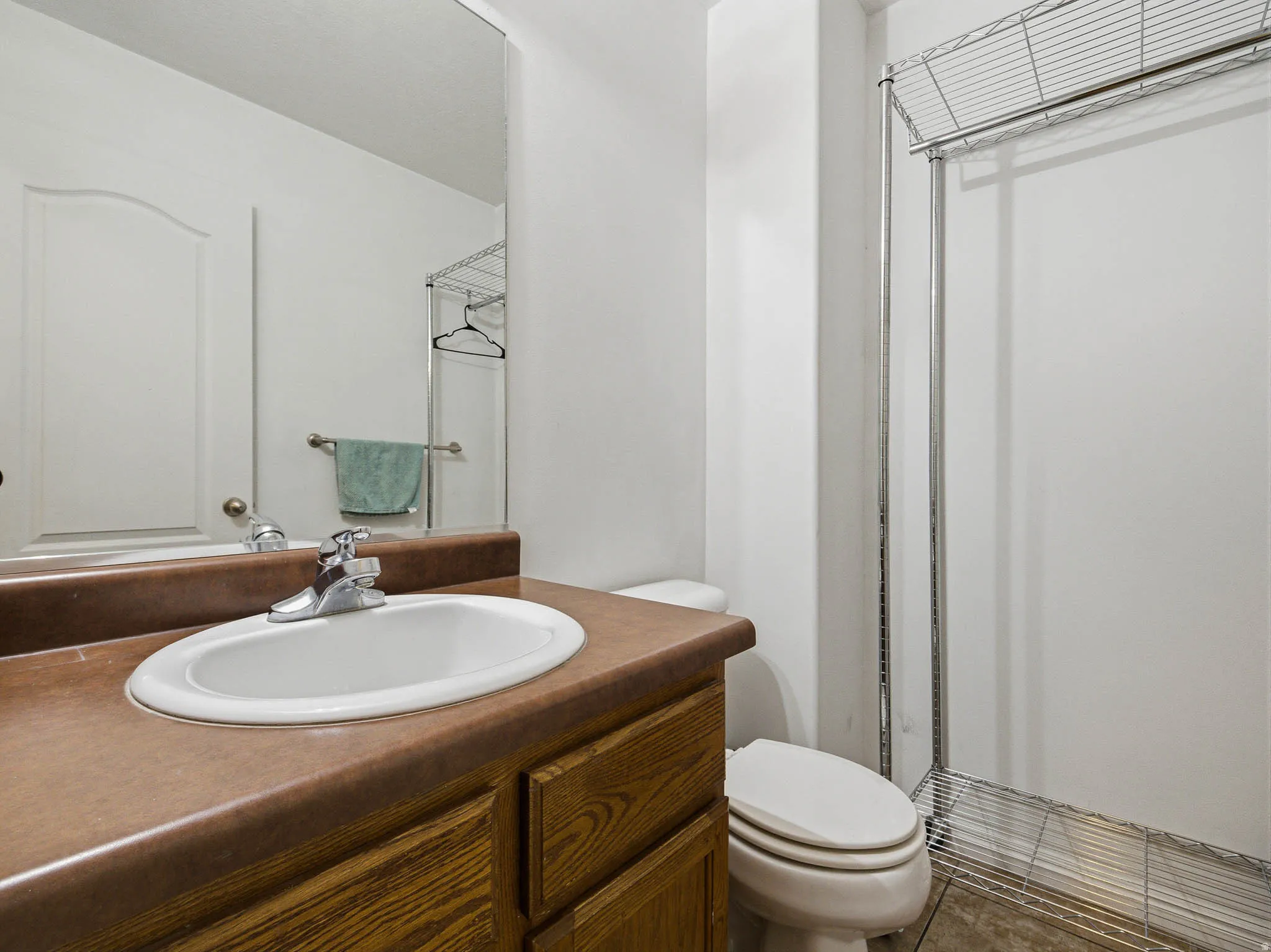 Bathroom vanity featuring a wood-finish cabinet, a brown countertop, and an oval undermount sink with a chrome faucet