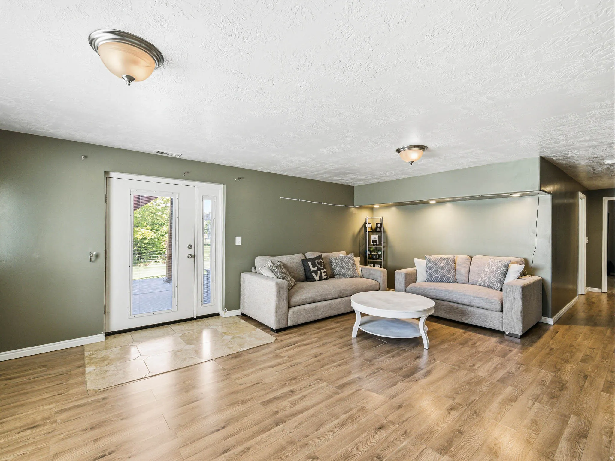 Spacious living area featuring wood-finish flooring, recessed lighting, and a neutral wall palette