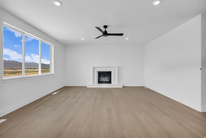 Spacious gathering room with energy efficient gas fireplace and contemporary ceiling fan, hard flooring throughout the entire main floor gathering areas.