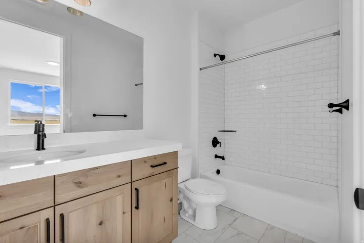 Personal guest suite's full bath featuring wood stained cabinetry with Quartz countertop featuring an extended edge profile, and matte black fixtures.