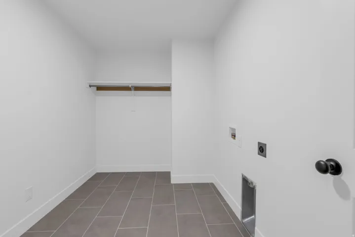 Utility room featuring gray plank-style tile flooring, and a built-in hanging rod with shelving.