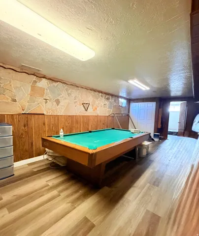 Recreation space featuring wood-finish flooring, stone accent wall, and wood paneling