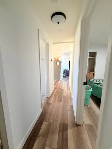 Hallway featuring wood-finish flooring, white baseboards, and a flush-mount ceiling light fixture