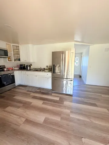 Kitchen featuring wood-finish flooring, white cabinetry, stainless steel appliances, and a built-in microwave