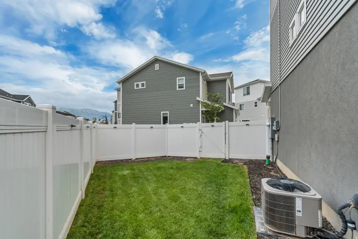 Private backyard featuring a manicured lawn, full vinyl fencing, and a side access gate
