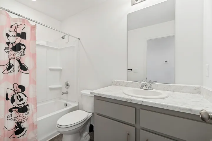 Bathroom featuring a tub/shower combination with white surround, a toilet, and a vanity with a white-finish sink