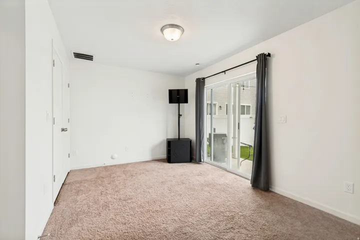 Carpeted room featuring a white ceiling and walls, recessed lighting, and a sliding glass door with dark fabric drapery